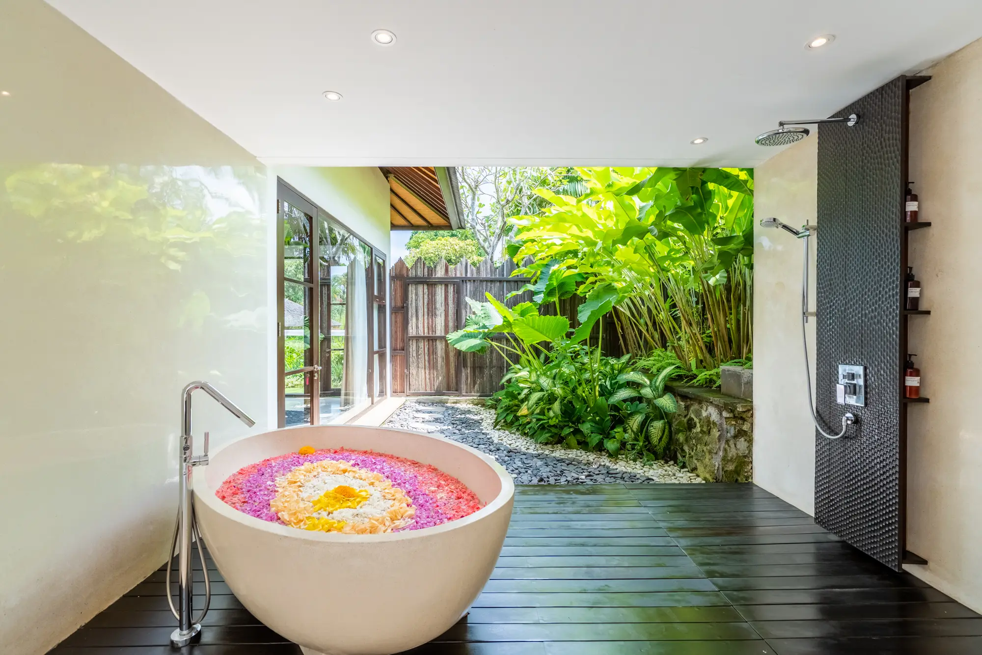 A stone bathtub filled with flowers in an outdoor bathroom