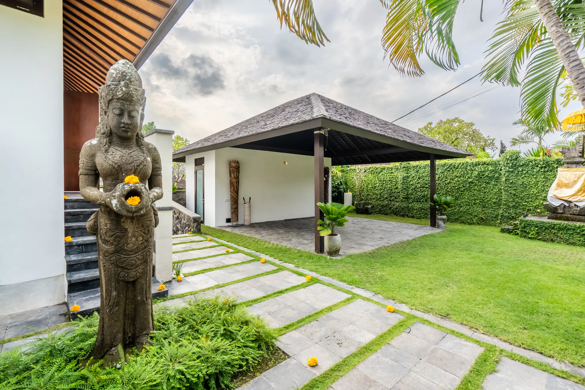 A stone statue in the garden beside a pavilion
