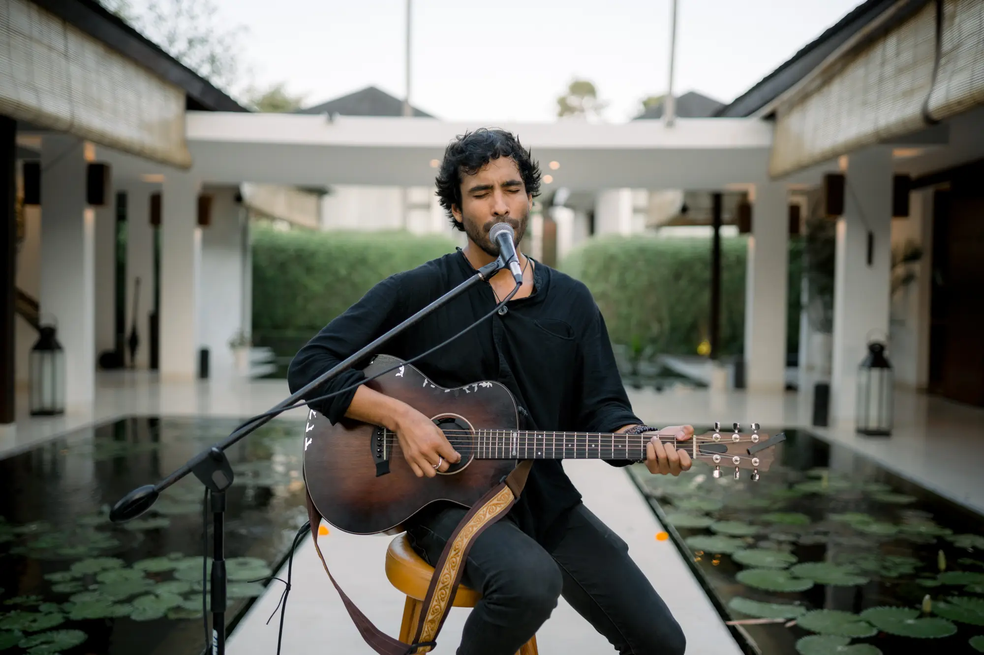 A musician playing guitar beside the lotus pond