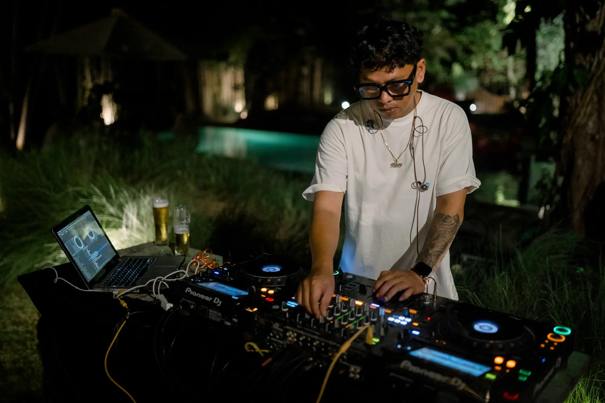 A DJ playing at a party in the garden at night