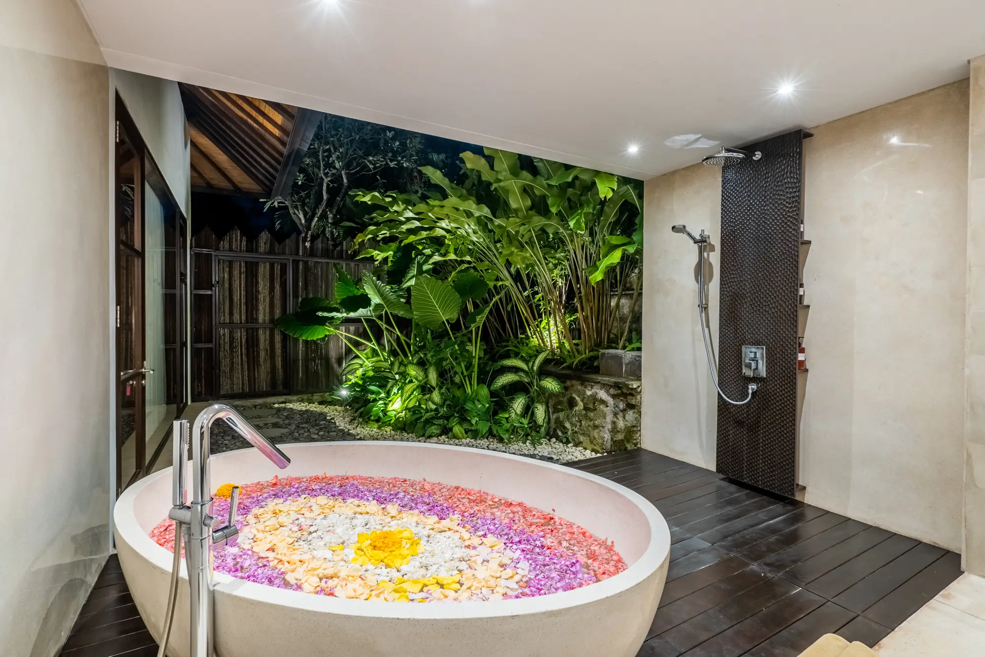 A round bathtub with flower petals in an outdoor bathroom