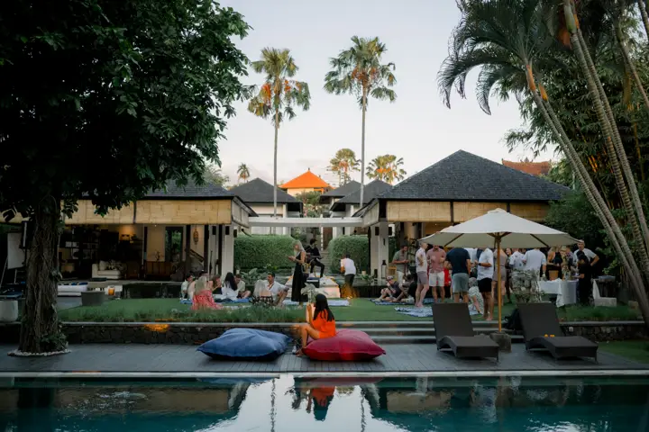 Guests on the pool deck and lawn at dusk