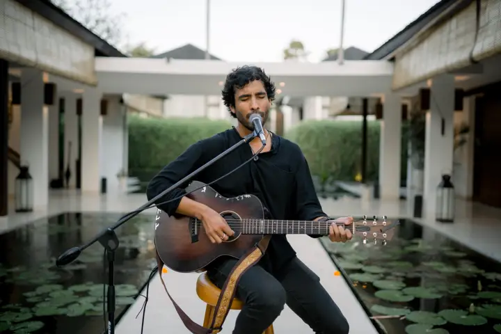 A musician playing guitar beside the lotus pond