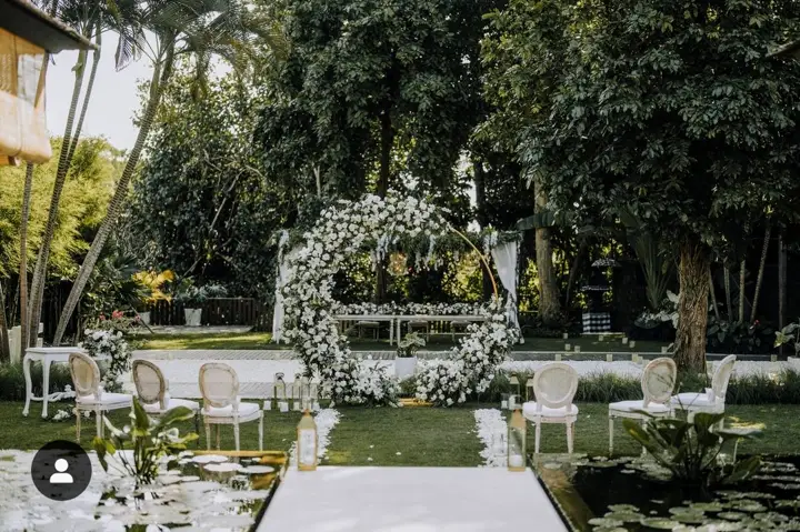 A wedding ceremony set up on the lawn with a floral arch