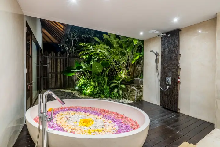 A round bathtub with flower petals in an outdoor bathroom